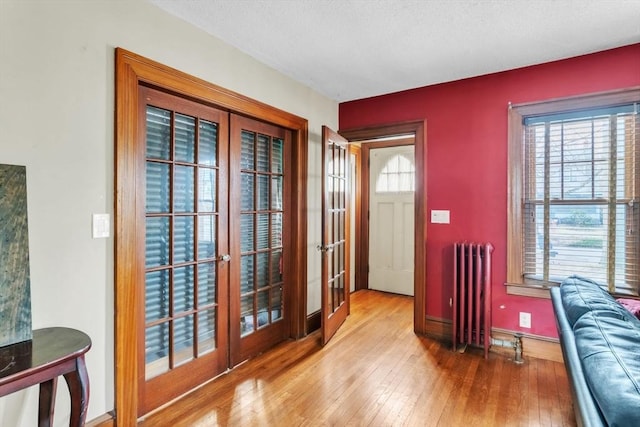 doorway to outside featuring light hardwood / wood-style floors, a textured ceiling, radiator, and french doors