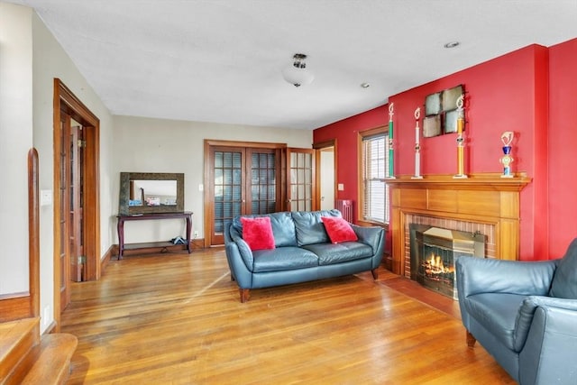 living room with wood-type flooring, radiator, and a fireplace