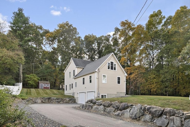 view of side of home with a yard, a garage, and a storage shed