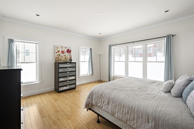 bedroom with light wood-type flooring, crown molding, and multiple windows