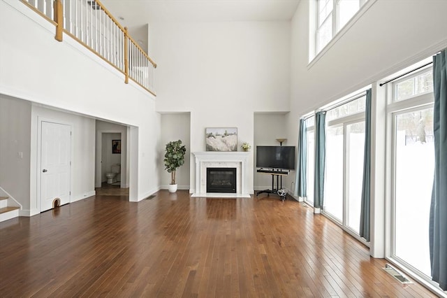 unfurnished living room with a high ceiling, a wealth of natural light, and a high end fireplace