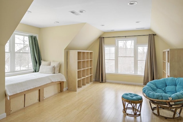 living area with a healthy amount of sunlight, lofted ceiling, and light wood-type flooring