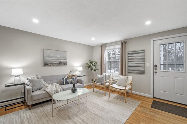 living area with light wood finished floors, baseboards, recessed lighting, a textured ceiling, and a baseboard radiator