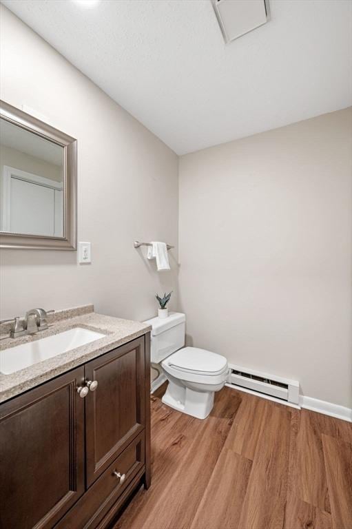 bathroom featuring baseboards, toilet, wood finished floors, vanity, and a baseboard radiator