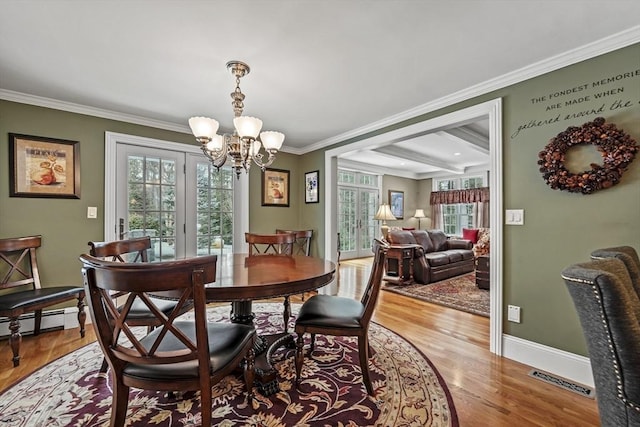 dining area with a notable chandelier, crown molding, a baseboard radiator, visible vents, and wood finished floors