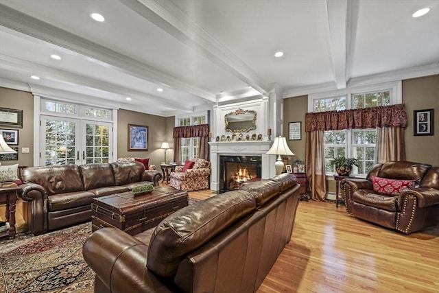 living area featuring a warm lit fireplace, french doors, ornamental molding, light wood-type flooring, and beamed ceiling