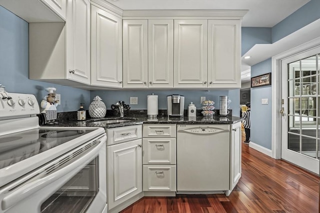 kitchen featuring white appliances, dark wood-style flooring, a sink, white cabinetry, and dark stone counters