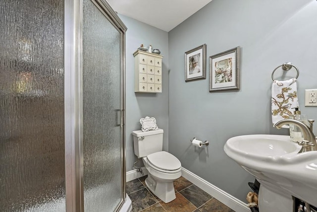 full bath with a stall shower, a sink, toilet, and baseboards