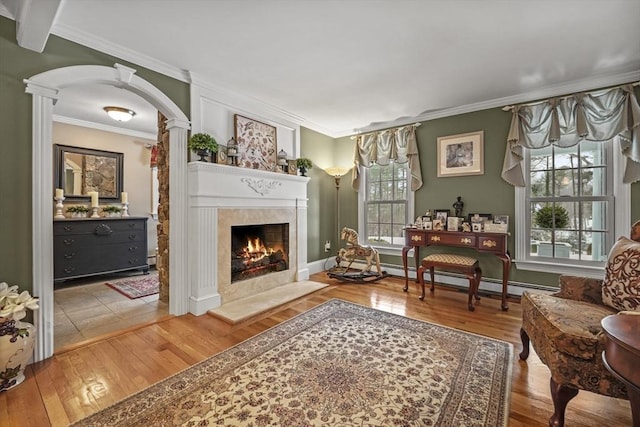 living area featuring a high end fireplace, a baseboard radiator, crown molding, and wood finished floors