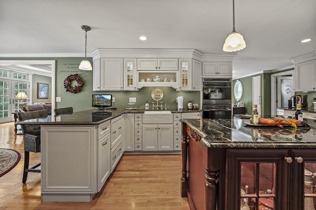 kitchen featuring white cabinetry, a breakfast bar area, glass insert cabinets, and pendant lighting