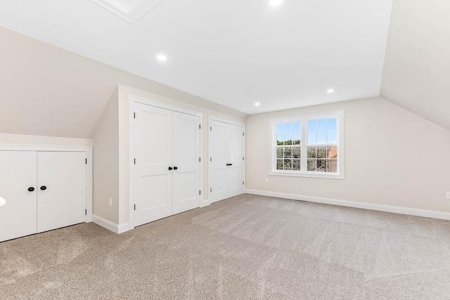 bonus room with vaulted ceiling and light carpet