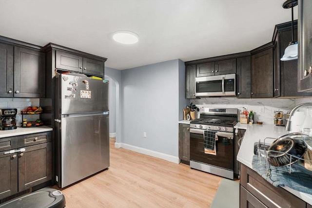 kitchen featuring appliances with stainless steel finishes, light countertops, dark brown cabinets, and light wood finished floors