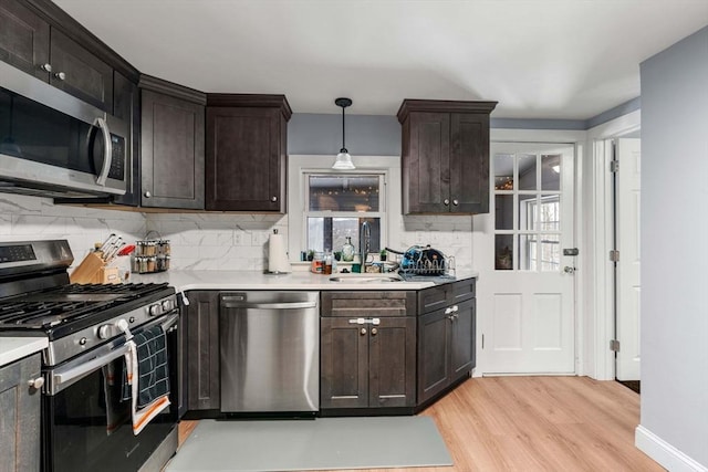 kitchen featuring appliances with stainless steel finishes, light countertops, dark brown cabinets, and pendant lighting