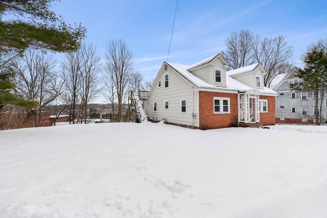 snow covered property featuring brick siding