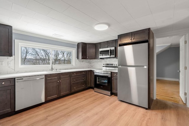 kitchen featuring a sink, light wood-style flooring, stainless steel appliances, and light countertops