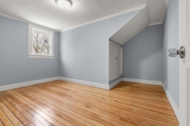 additional living space with light wood-style flooring, baseboards, and vaulted ceiling