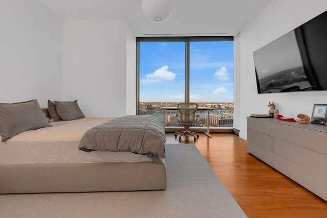 bedroom with a wall of windows and wood finished floors