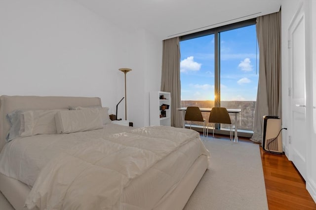 bedroom featuring expansive windows and wood finished floors