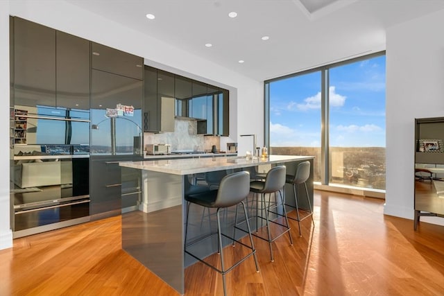 kitchen with a breakfast bar, floor to ceiling windows, backsplash, light wood-style floors, and modern cabinets