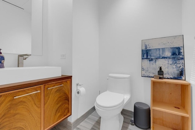 bathroom with baseboards, vanity, toilet, and wood finished floors