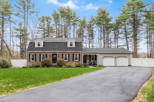 colonial inspired home featuring a front lawn, aphalt driveway, brick siding, an attached garage, and fence