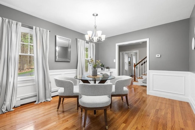 dining room with a chandelier, plenty of natural light, a decorative wall, and wainscoting
