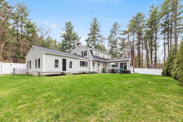 view of front of house with a front lawn, a gate, a fenced backyard, and a chimney