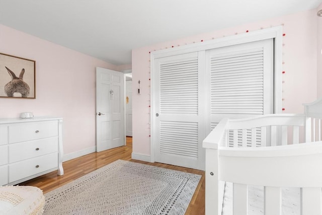 bedroom with a closet, light wood-style flooring, and baseboards