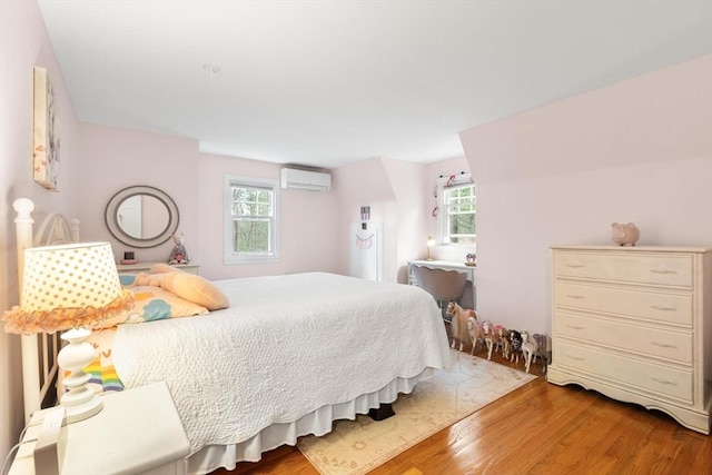 bedroom featuring a wall mounted air conditioner and wood finished floors