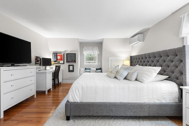 bedroom with wood finished floors, a wall mounted air conditioner, and baseboards