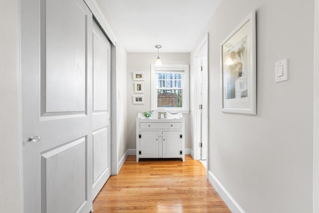 hallway featuring light wood-style flooring and baseboards