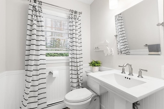 bathroom featuring toilet and a wainscoted wall