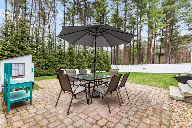 view of patio featuring an outbuilding, outdoor dining space, and a fenced backyard