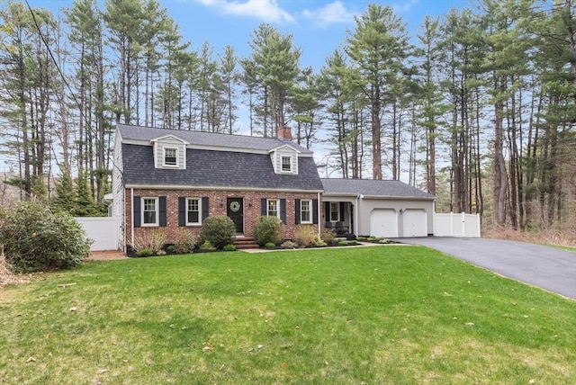 colonial inspired home with driveway, fence, brick siding, and a garage