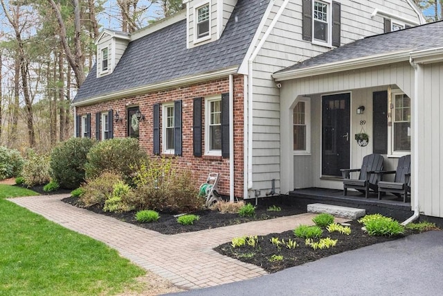 property entrance with roof with shingles and brick siding