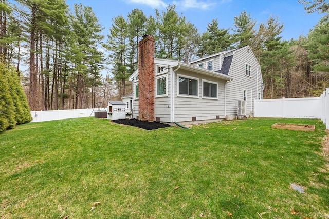 view of side of home with a lawn, a gambrel roof, a fenced backyard, and a chimney
