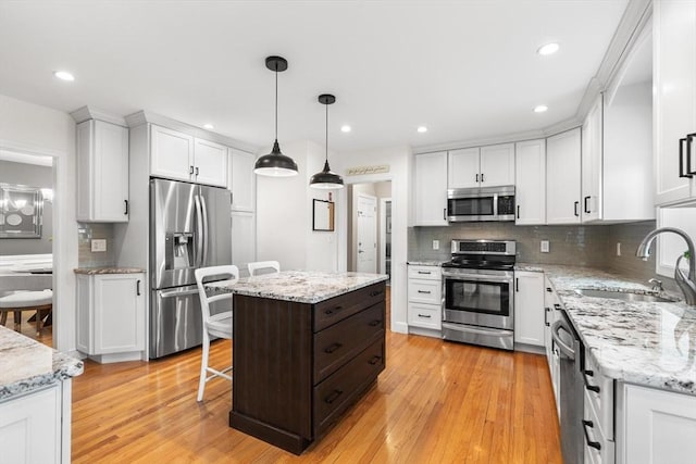 kitchen with decorative backsplash, appliances with stainless steel finishes, a sink, white cabinetry, and light wood-type flooring