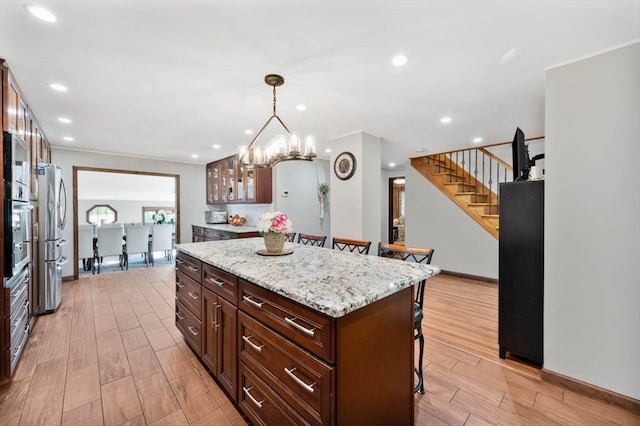 kitchen featuring light stone counters, a center island, light hardwood / wood-style floors, pendant lighting, and a breakfast bar area