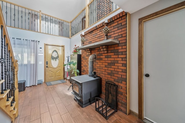 foyer featuring a towering ceiling, hardwood / wood-style flooring, and a wood stove