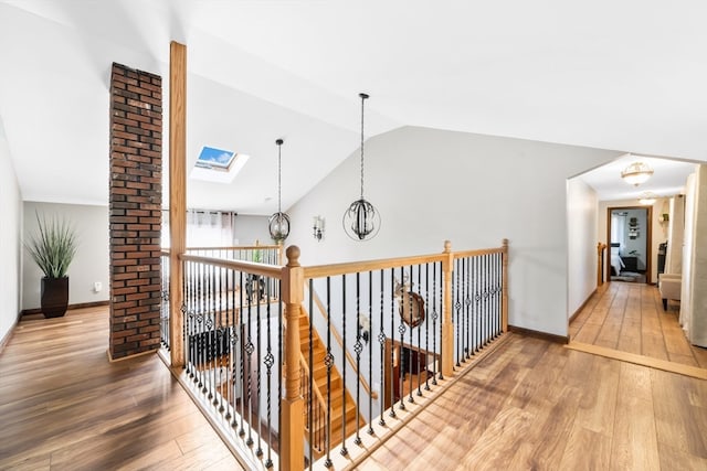 corridor with wood-type flooring, an inviting chandelier, and vaulted ceiling with skylight