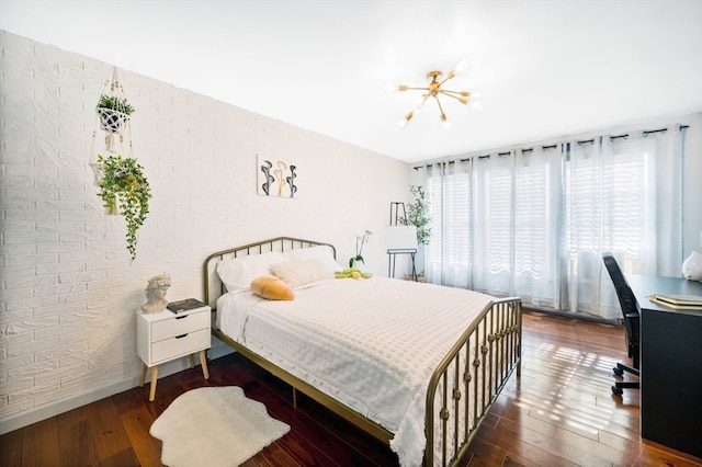 bedroom with dark hardwood / wood-style floors, brick wall, a chandelier, and multiple windows