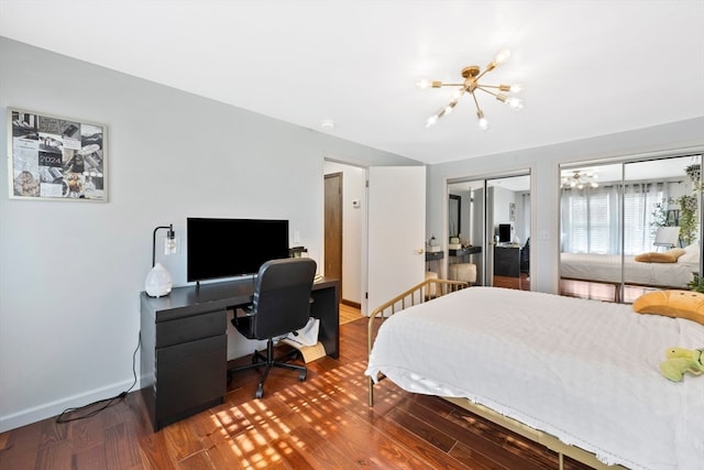 bedroom featuring wood-type flooring, two closets, and a chandelier