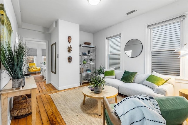 living area featuring light wood finished floors, baseboards, and visible vents