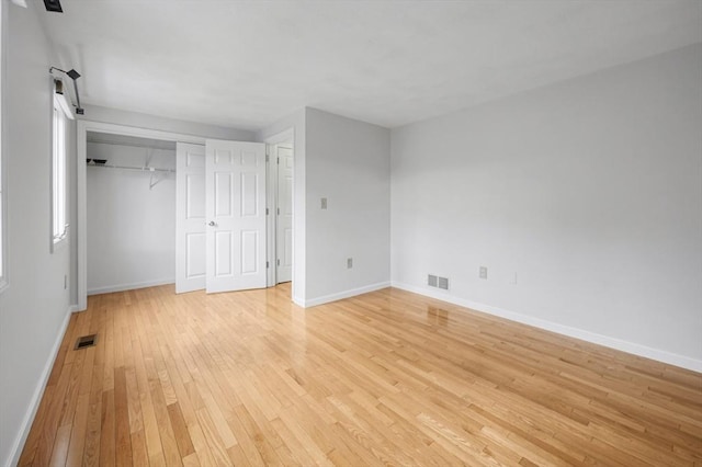 unfurnished bedroom with visible vents, baseboards, light wood-style floors, and a closet