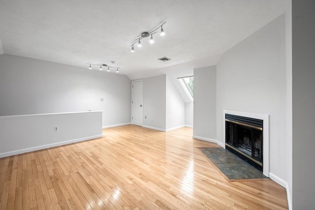 unfurnished living room with hardwood / wood-style floors, baseboards, visible vents, lofted ceiling, and a tile fireplace