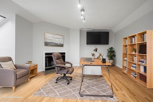 office with vaulted ceiling, rail lighting, wood finished floors, and baseboards