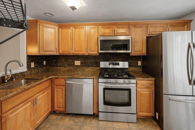 kitchen featuring a sink, dark stone counters, tasteful backsplash, and appliances with stainless steel finishes