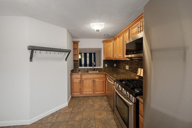 kitchen with a sink, a textured ceiling, stainless steel appliances, brown cabinetry, and decorative backsplash