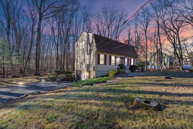 property exterior at dusk featuring a yard