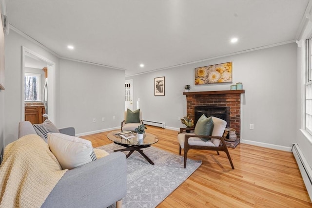 living room with a baseboard heating unit, a brick fireplace, crown molding, and light hardwood / wood-style flooring